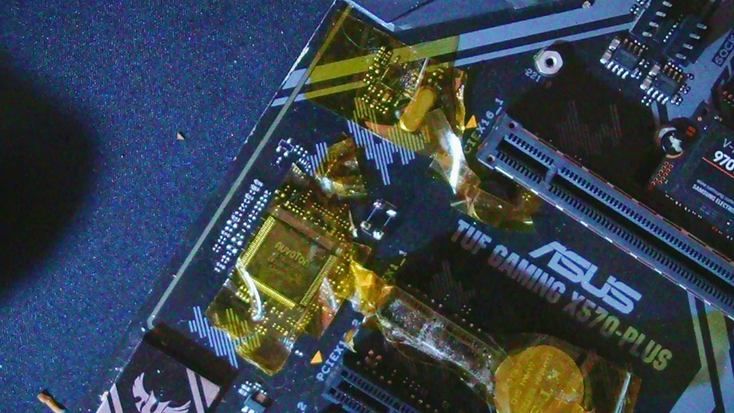 Close view of the X570-Plus board with Kapton tape masking the components around the chipset and CMOS-battery area during rework.